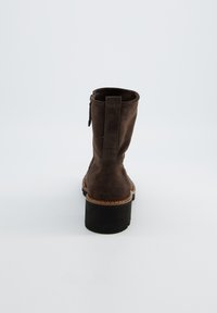 Bruine suède enkellaars met een iets verhoogde zwarte rubberen zool, ritssluitingen aan de zijkant en een kleine trekband achter.