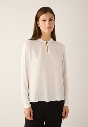 White long-sleeve blouse with a high neckline and a keyhole detail, featuring soft, lightweight fabric and slightly gathered sleeves.