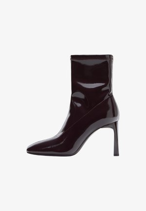 Bottines en cuir verni bourgogne avec un bout pointu et un tige ajustée et profilée. Présente un talon aiguille haut et des coutures apparentes.