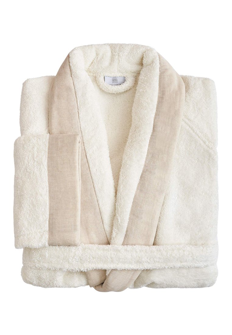 Witte pluche badjas met een zachte badstof textuur. Heeft een beige linnen bies langs de kraag en de zak. De gevouwen stijl toont de combinatie van stoffen.