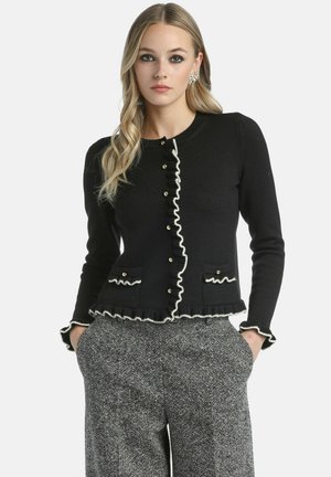 Cardigan nero con dettagli in raso bianco, apertura con bottoni e due tasche. Realizzato in un tessuto a maglia testurizzato, vestibilità su misura.