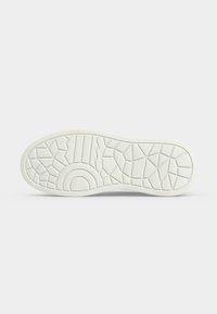 Semelle de chaussure blanche avec motifs géométriques sur la semelle, comprenant des hexagones, des lignes, des triangles et un demi-cercle sur un fond uni.