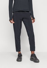 Sorte treningsbukser med et strømlinjeformet design, laget av lett materiale. Har en subtil Nike-logo på venstre side.