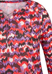 Mehrfarbiger Oberteil mit einem wellenförmigen Muster in Rot, Lila und Schwarz, V-Ausschnitt und Kordelzugdetails. Hergestellt aus einem glatten, leichten Stoff.