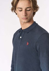 Polo blu navy in cotone, con colletto, patta con due bottoni e un piccolo logo rosso sul petto.