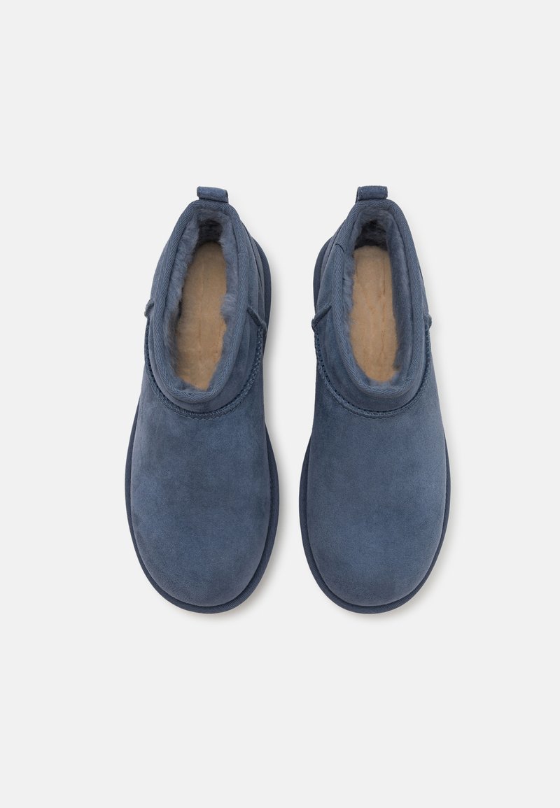 Blaue Wildleder-Stiefeletten mit weicher Fell-Innenseite und runder Zehenform, ausgestattet mit einem niedrigen Absatz und ohne sichtbare Beschläge oder Akzente.
