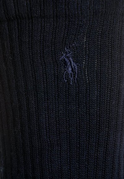 Navy zila ribota adījummateriāla audums ar nemanāmu izšūtu zirga logo, pievienojot tekstūru un detaļas apģērbam.