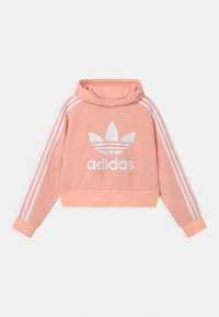 Hoodie court rose avec un logo blanc et trois rayures blanches sur les manches. Tissu doux, capuche à cordon de serrage, poignets côtelés.