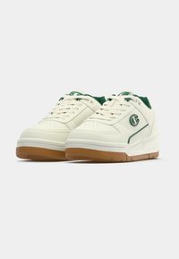Λευκά δερμάτινα αθλητικά παπούτσια με πράσινες λεπτομέρειες, διαθέτουν επενδεδυμένο γιακά, διάτρητη μύτη και σόλα από καουτσούκ καραμέλας. Λογότυπο στη πλευρά.