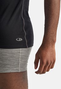 Svart treningsgenser med grå kant, kombinert med lysegrå shorts. Merkverdig logo på skjorten, som viser en tettsittende design og myk tekstur.
