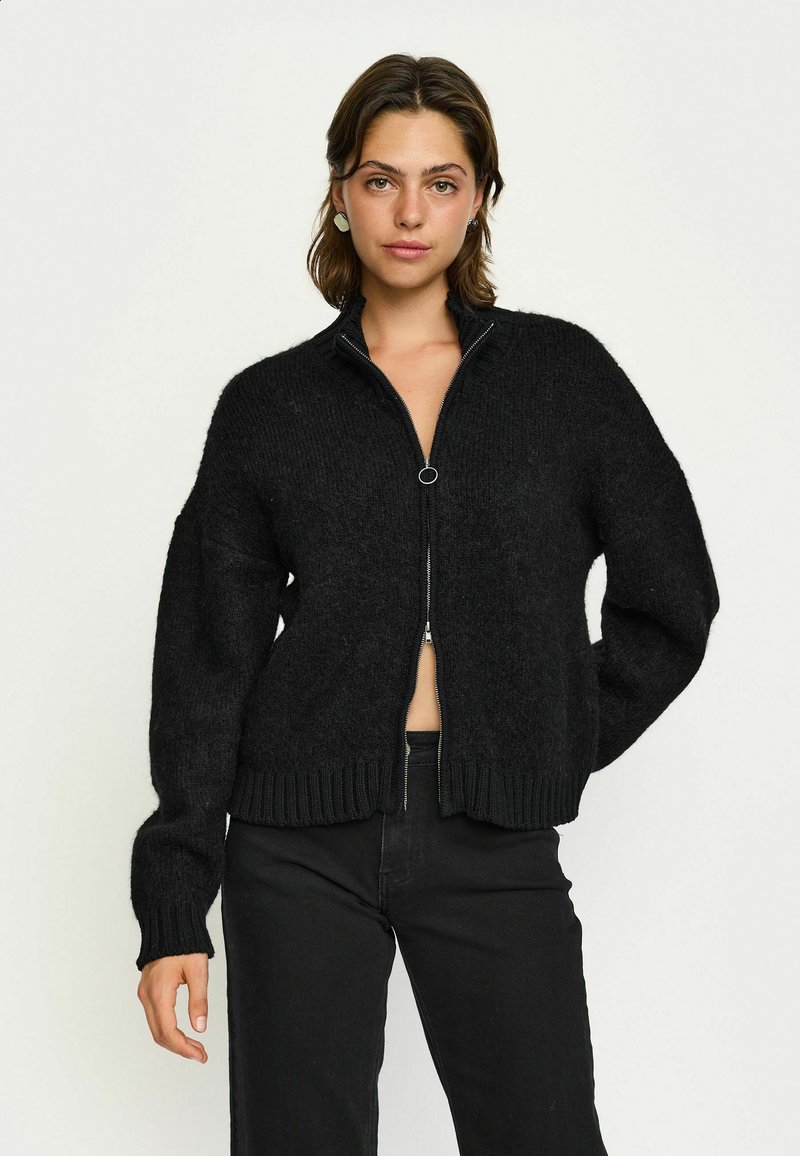 Schwarzer Reißverschluss-Pullover in grober Strickoptik, mit hohem Kragen, gerippten Bündchen und Saum, lockerer Passform und weicher Textur.