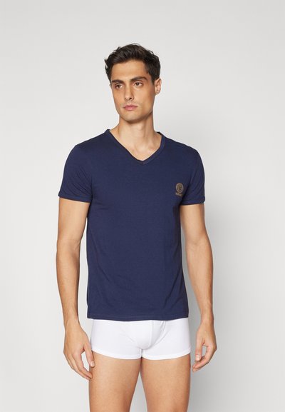 T-shirt in cotone blu navy con scollo a V, maniche corte e un piccolo logo sul petto sinistro. Il modello indossa boxer bianchi.