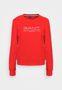 Rode trui van zachte stof met een ronde hals, geribde manchetten en zoom. Voorzien van een witte tekstlogo: "GANT AMERICAN SPORTSWEAR SINCE 1949."