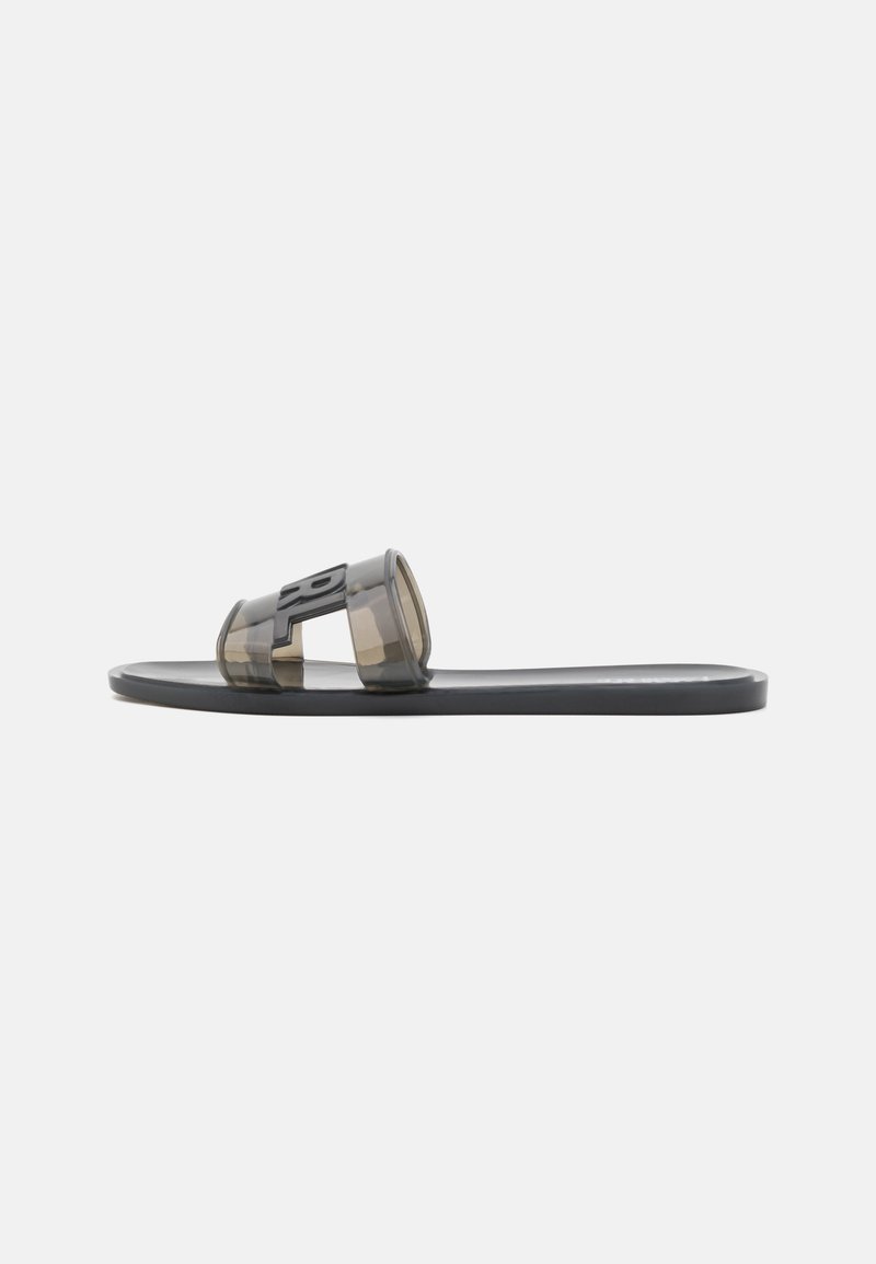 Sandalha plana preta com tiras cinzas transparentes. Apresenta um design em duas partes com um detalhe de logótipo proeminente. Sola leve e suave.