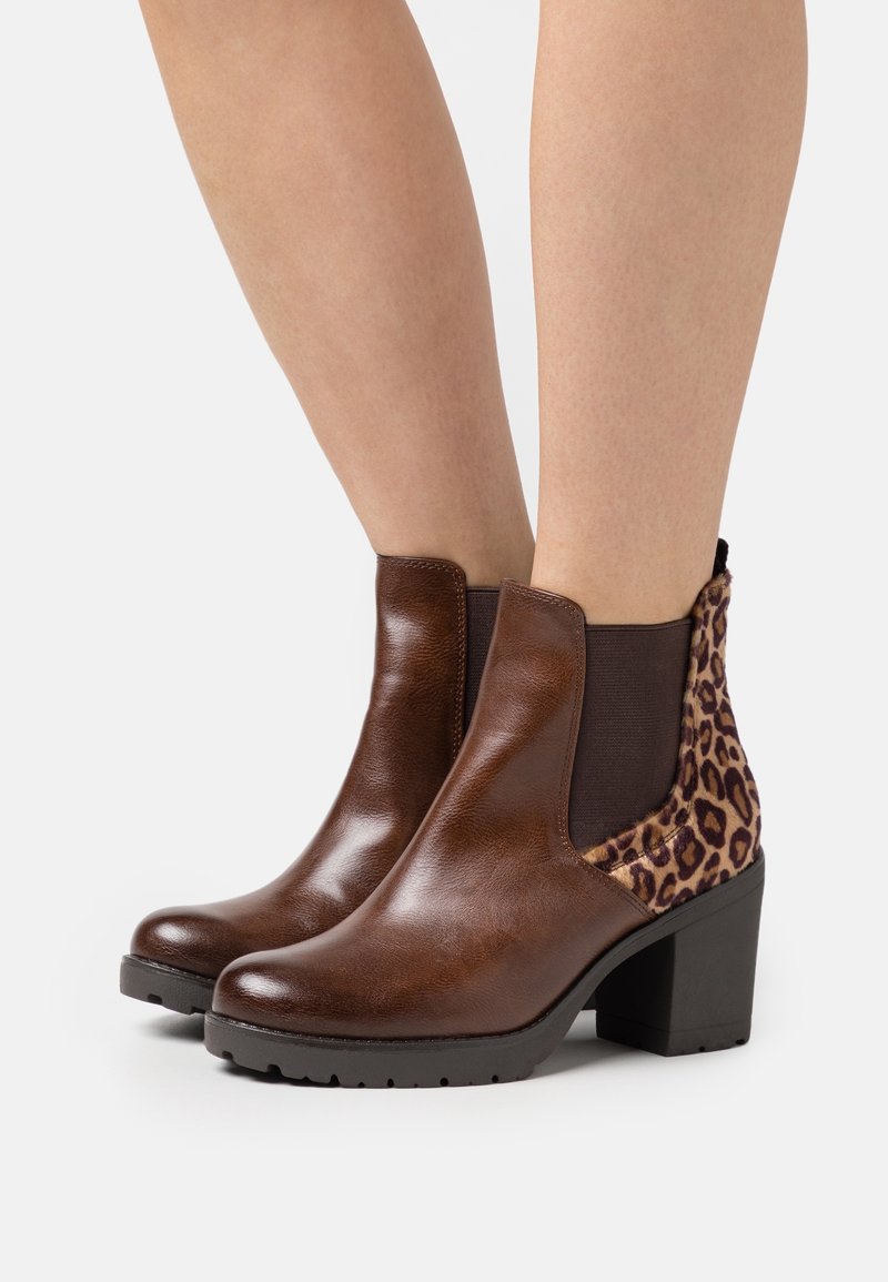 Bottines en cuir marron avec un panneau latéral imprimé léopard, bout rond et talon bloc. Équipées d'un élastique pour faciliter l'enfilage.