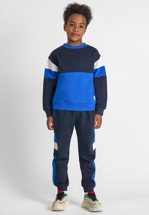 Blau und marinefarbener color-blocked Sweatshirt mit weißen Akzenten, kombiniert mit passenden Hosen, die blaue und weiße Streifen aufweisen. Hergestellt aus weichem Stoff.
