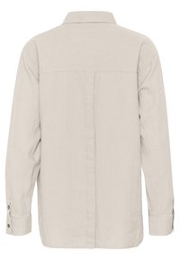 Light beige long-sleeve shirt with a collared neckline. Made of linen, featuring a straight back seam and buttoned cuffs. Simple, textured fabric.