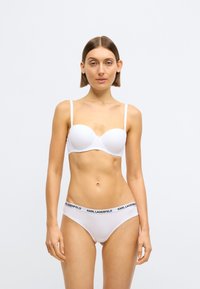 Bílá podprsenka s vycpávkami s tenkými ramínky a bílé kalhotky s černým pasem s nápisem "KARL LAGERFELD".