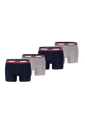 Muskolöser Mann trägt marineblaue Levi's Boxershorts mit weißem, rotem und marineblauem Bund, steht vor einem weißen Hintergrund.