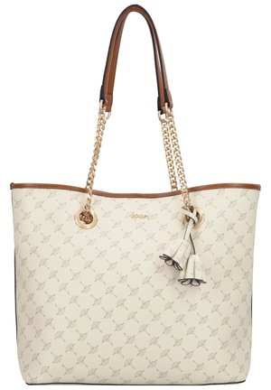 Bolsa tote color crema con pequeño patrón geométrico, ribete marrón, asas de cadena dorada y adorno de tassel floral colgando cerca del centro superior.