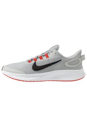 Szary but do biegania z siateczki z czarnym logo Swoosh, białą podeszwą oraz czerwonymi pętelkami na sznurówki i czerwonymi akcentami na zewnętrznej podeszwie, widok z boku.