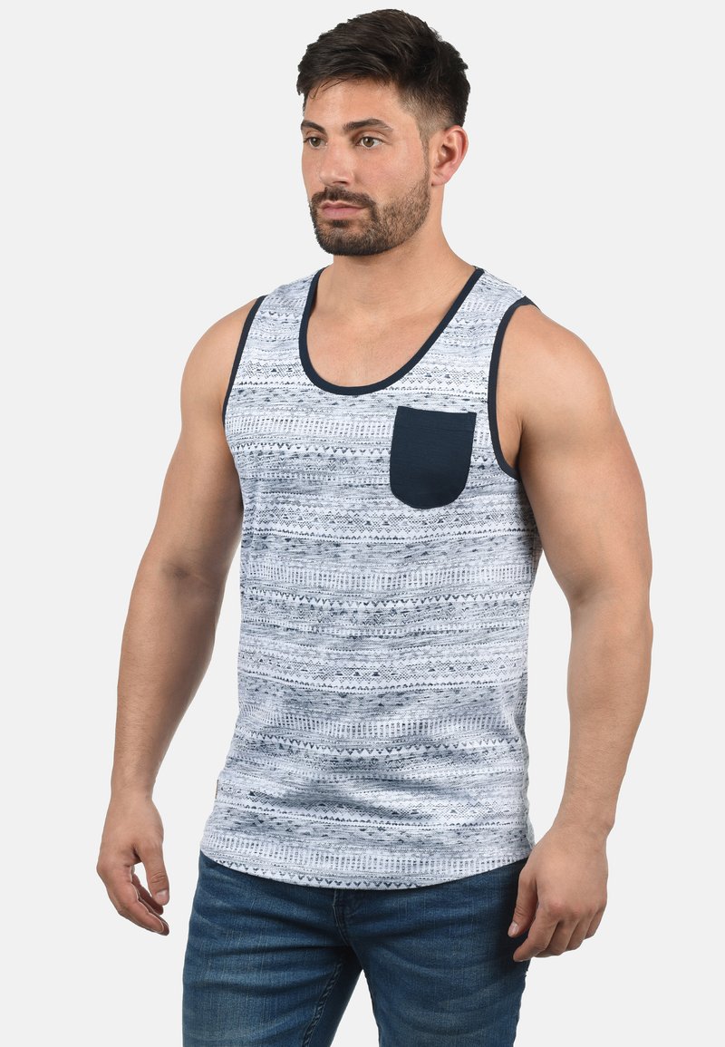 Ermeløs herre tank-top i lys blå med marineblå akenter og en lomme. Har et strukturert, mønstrete design over hele. Blandingsmateriale av bomull.
