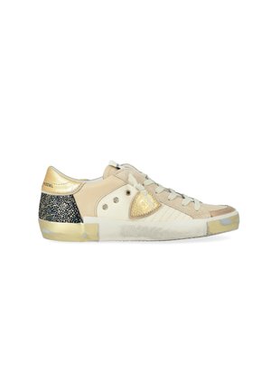 Sneaker beige a basse, con lacci bianchi, dettagli dorati, tallone maculato di nero e suola bianca leggermente usurata.