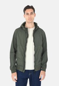 Giacca con cappuccio verde oliva realizzata in materiale leggero, con zip frontale completa, polsini elasticizzati e vestibilità comoda. Texture liscia.