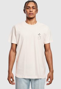 Kortærmet, lyseblå bomuld t-shirt med en lille sort kontur af en vase med blomster på venstre bryst. Klassisk rund halsudskæring.