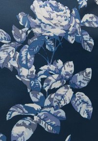 Wzór tkaniny w kwiaty przedstawiający białą i jasnoniebieską różę z ciemnoniebieskimi liśćmi, na granatowym tle. Teksturowany splot dodaje głębi.