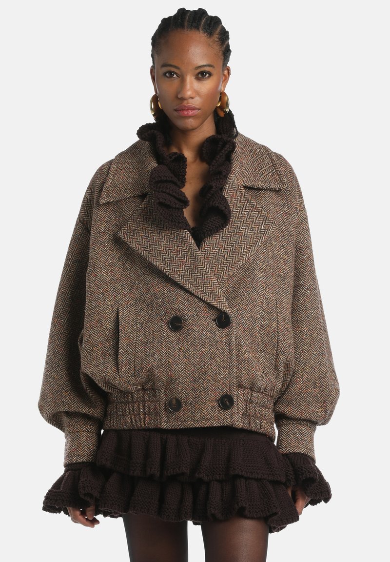Brown houndstooth cropped jacket with a double-breasted design, oversized sleeves, and a black ruffled collar. Features large buttons.