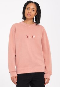 Rosa Sweatshirt mit gerippten Bündchen und Saum, versehen mit einem stilisierten "Volcom"-Logo in kontrastierenden Farben auf der Brust. Hergestellt aus weichem Stoff.