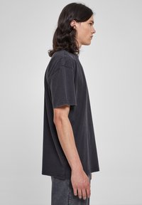 Tricou cu mânecă scurtă, lejer, din bumbac negru spălat, cu decolteu rotund și cusături contrastante pe mâneci și tiv.