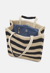 Sac fourre-tout tissé beige et noir à rayures, doté de deux poignées et d'une doublure intérieure bleue avec une poche zippée munie d'un gland en guise de tirette.