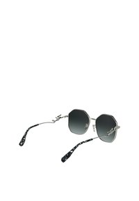 Occhiali da sole ottagonali con montatura in argento metallico, lenti a gradiente scuro e puntali neri e bianchi con motivo. Dettaglio inciso sulla montatura.