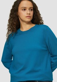 Turquoise trui, ronde hals, lange mouwen, lichtgewicht stof, gladde textuur, ontspannen pasvorm, minimale naden, geen zichtbare patronen of versieringen.