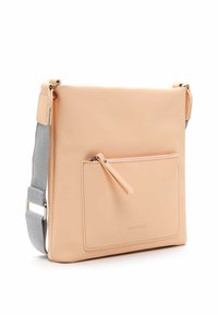 Zezadu crossbody taška v broskvové barvě s hladkým povrchem, nastavitelným šedým popruhem a přední kapsou na zip s úzkou poutkou.