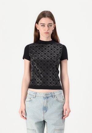 Černý top s krátkým rukávem a texturovaným geometrickým mřížkovým vzorem, s ne příliš vysokým límečkem a přiléhavým střihem, doplněný o světle modré džíny.