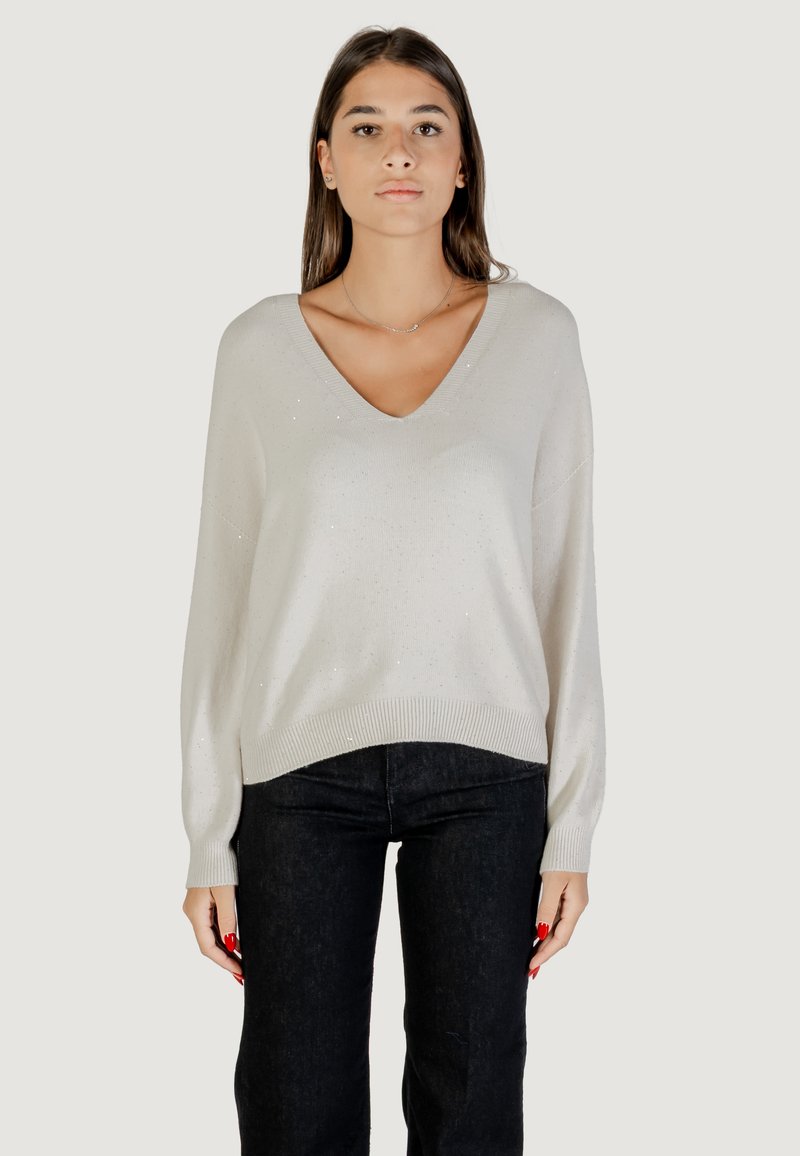 Pull V en gris clair avec des manches longues, présentant un léger éclat et un ourlet côtelé, associé à un jean en denim foncé.
