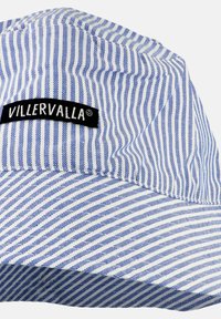 Cappello di stoffa a righe blu e bianche con un'etichetta nera del marchio Villervalla cucita sul lato.