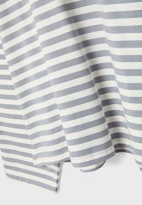 Valkoinen ja harmaa vaakasuunnassa raidallinen kangas, jossa näkyvät saumanompeleet ja kevyitä laskoksia, jotka viittaavat pehmeään, kevyesti kudottuun kangasmateriaaliin.