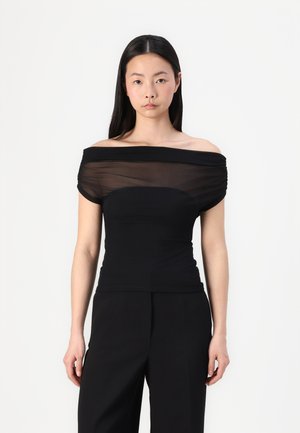 Black off-the-shoulder top with sheer fabric at the neckline; fitted bodice, smooth texture, and gathered detailing on sleeves.