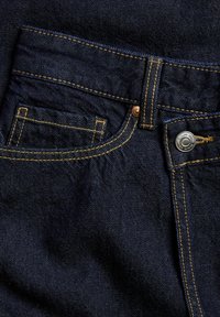 Donkerblauwe denim jeans met een gedefinieerde tailleband, koperen hardware en gele stiksels. Heeft een klein voorzakje en een gladde textuur.