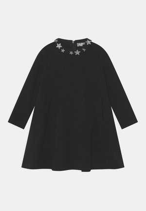 Schwarzes Kleid mit langen Ärmeln, rundem Ausschnitt und sternförmigen Verzierungen am Kragen. A-Linien-Form und Reißverschluss auf der Rückseite.