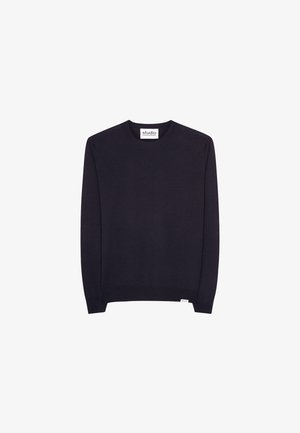 Pulli aus dunklem marineblauen Strick, runder Ausschnitt; kombiniert mit weiten schwarzen Hosen und weißen Sneakers. Minimalistisches Design, keine sichtbaren Muster oder Logos.