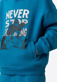 Modra majica s kapuco z grafičnim potiskom z napisom "NEVER STOP EXPLORING." Vključuje žep za kenguru in rebraste manšete ter spodnji rob.