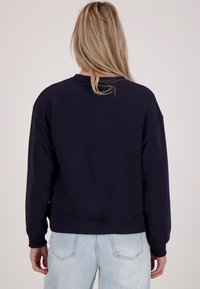 Marineblauwe sweatshirt met een relaxte pasvorm, ribgebreide manchetten en zoom, en een ronde hals, gemaakt van een zachte, gestructureerde stof.