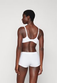 Ensemble de soutien-gorge et culotte seamless blancs. Matière douce et lisse avec des bretelles réglables et un design simple. Pas de motifs visibles ni de détails matériels.