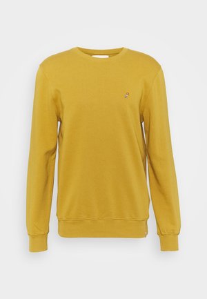 Sennepsgul langærmet crewneck-sweatshirt med ribstrikkede manchetter og fornede kanter, med et lille broderet multifarvet logo på venstre bryst.