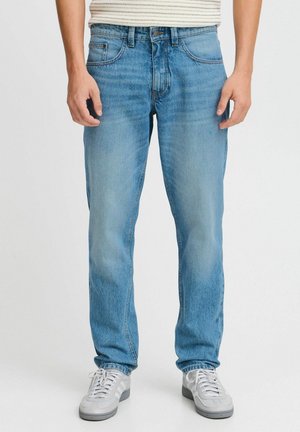 Ljust blå denimjeans med rak passform, som har en klassisk femfickdesign och subtila blekningar, i kombination med vita sneakers.